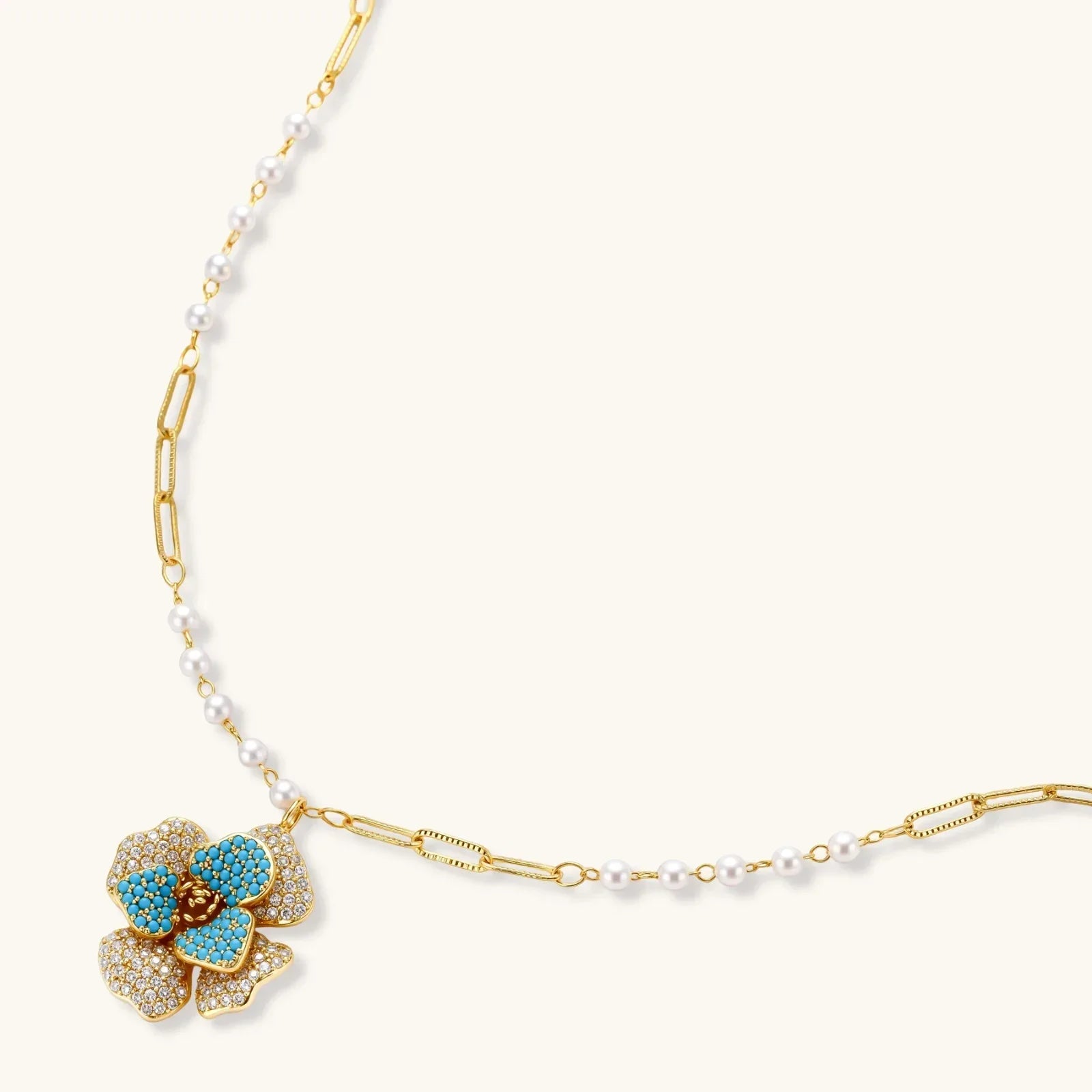 14K gold-plated floral jewelry set with blue cubic zirconia centers and pearl chain details on white background.