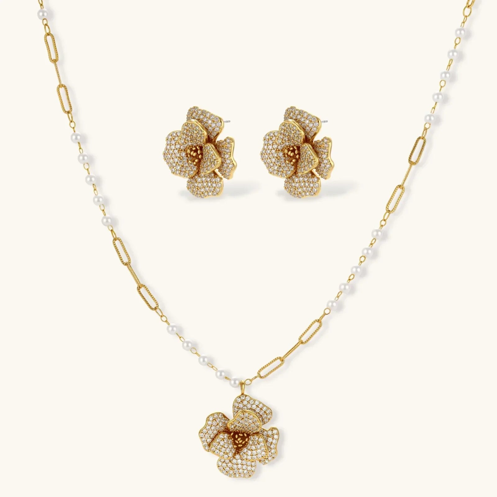 14K gold-plated floral jewelry set with blue cubic zirconia centers and pearl chain details on white background.