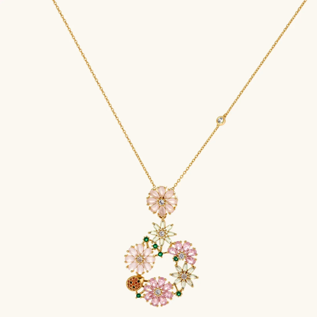 14K gold plated jewelry set with pink and green cubic zirconia flowers arranged in wreath design on cream background