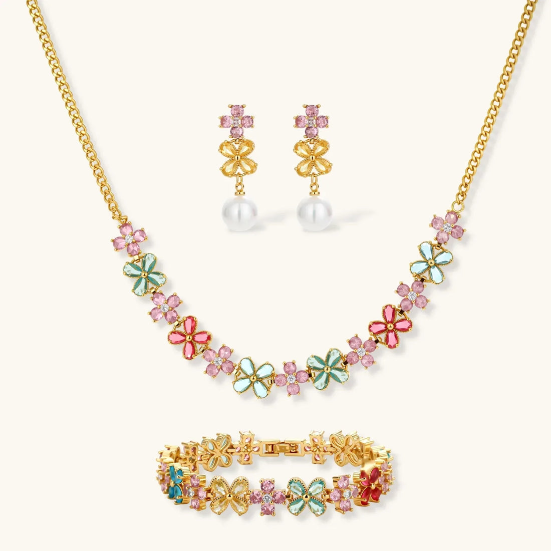 Gold-plated jewelry set with pink, turquoise and red flower-shaped cubic zirconia stones, featuring necklace, earrings and bracelet.