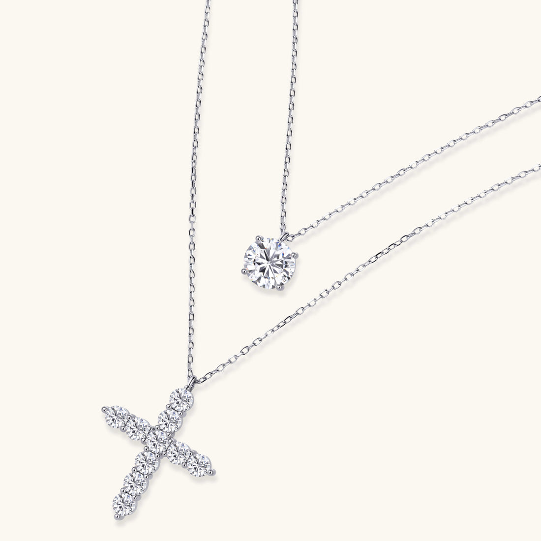 Two delicate sterling silver necklaces with moissanite stones - one solitaire pendant and one cross pendant on white background.